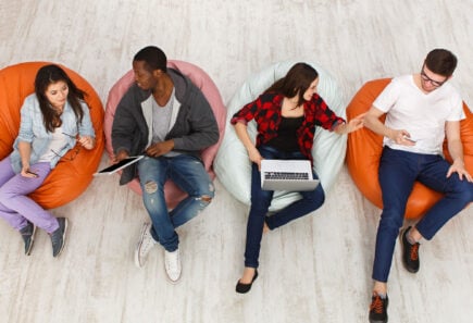 students sitting in bean bag chairs talking and working on laptops
