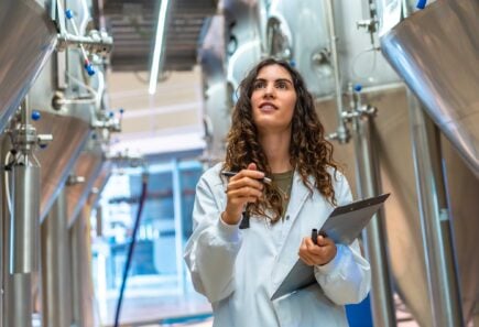 Female scientist walking between fermentation tanks
