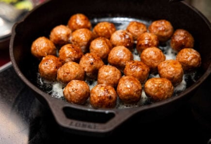 Cultivated pork fat meatballs sizzling on a skillet