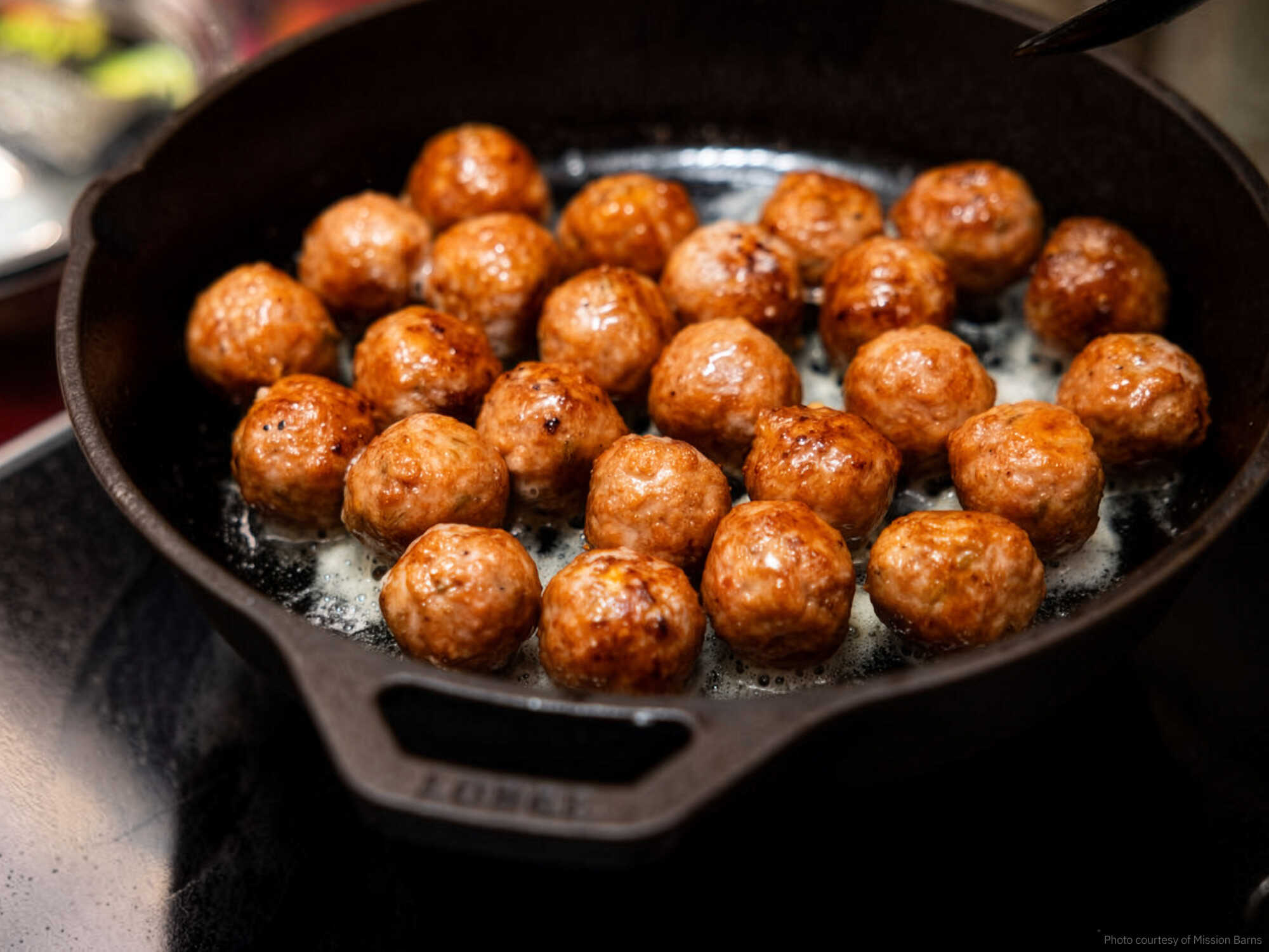 Cultivated pork fat meatballs sizzling on a skillet