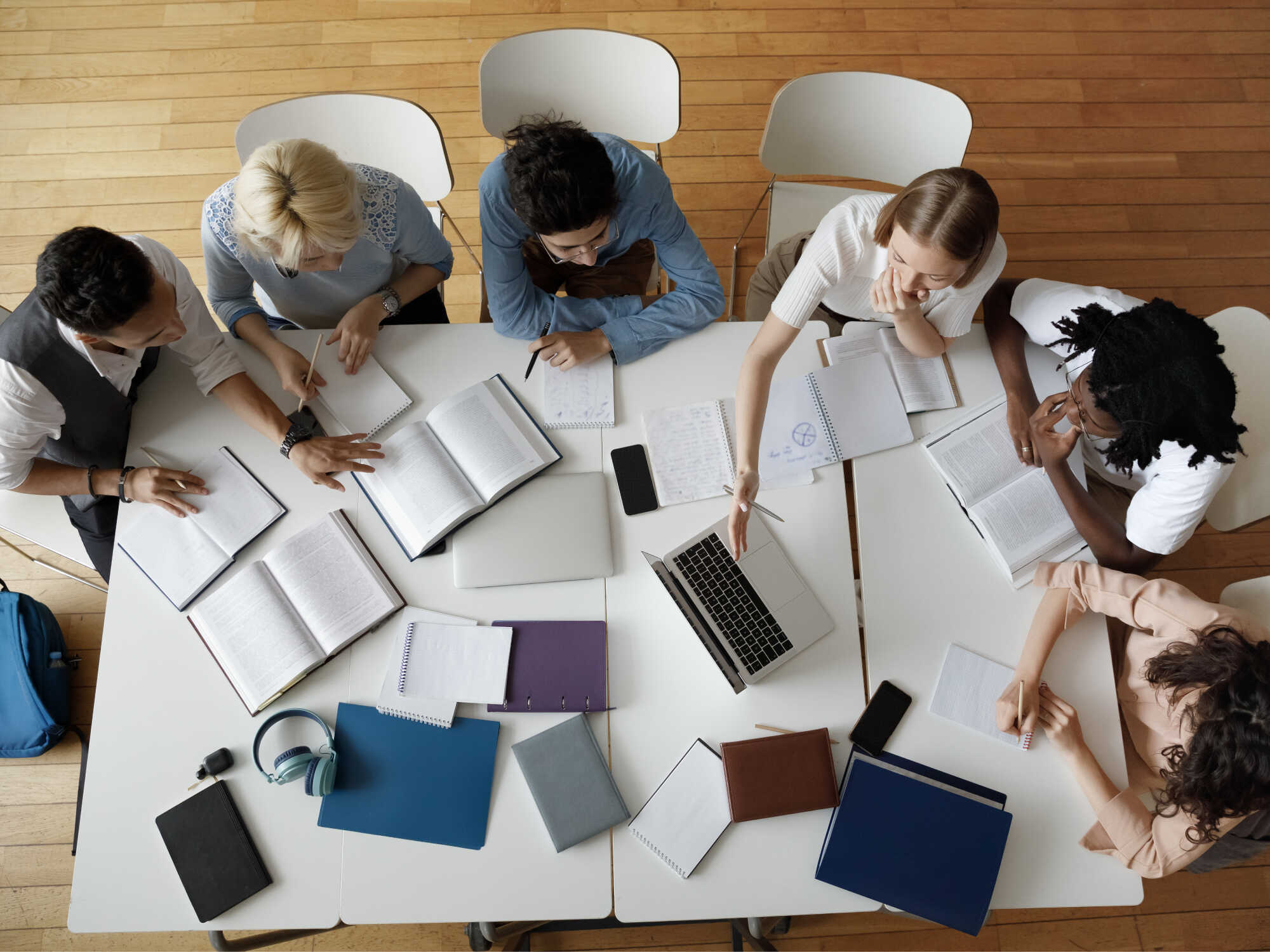 A group of people at a table with notebooks and laptops