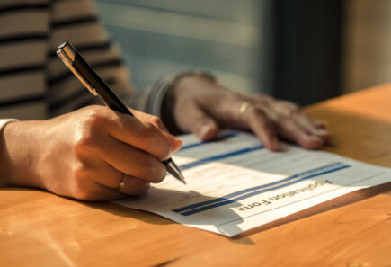 A close-up view of a person filling in an application form