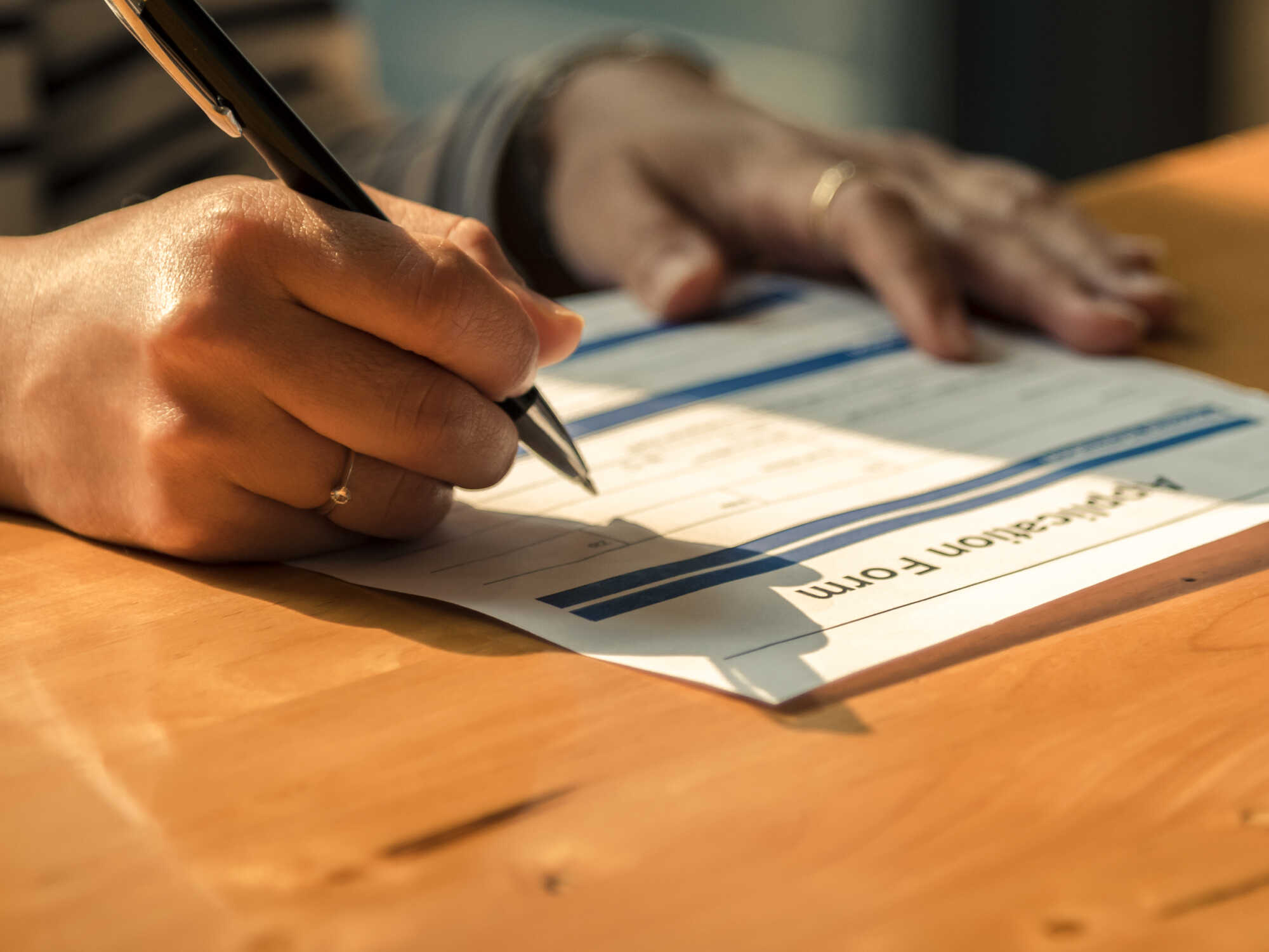 A close-up view of a person filling in an application form