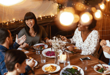 A diverse group of people smiling and enjoying a meal together