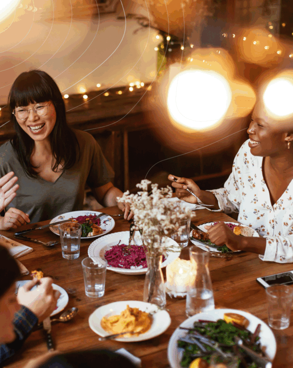 A diverse group of people smiling and enjoying a meal together